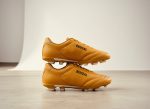 “Stylish golden Bengal football boots for men with white logo, durable design for soccer and turf play, shown with box.”