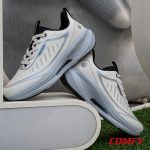 Pair of white athleisure sports shoes for men casually displayed outdoors against a modern backdrop and green grass.