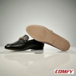 Black and brown chain loafers on a reflective surface, with the brown loafer showing its textured beige sole.