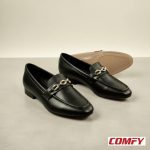 Two black chain loafers in the foreground, with a brown chain loafer in the background, all on a light gray surface.