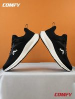 Symmetrical shot of two black women's running shoes touching toes.