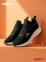 Stylish pair of black athletic running shoes for women on an orange display ledge.