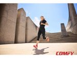 Woman wearing orange CRIVIT running shoes training outdoors near concrete stairs.