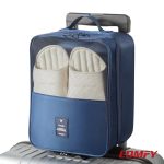 Blue travel shoe bag secured on the telescopic handle of a silver rolling luggage suitcase.