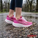 Side view of pink and purple Reebok sneakers on a wet gravel path.